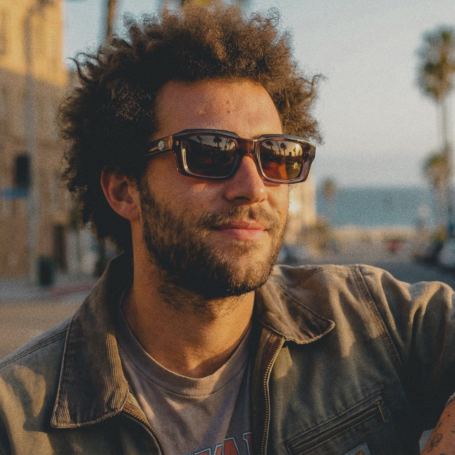 Man wearing sunglasses on a city street with palm trees in the background
